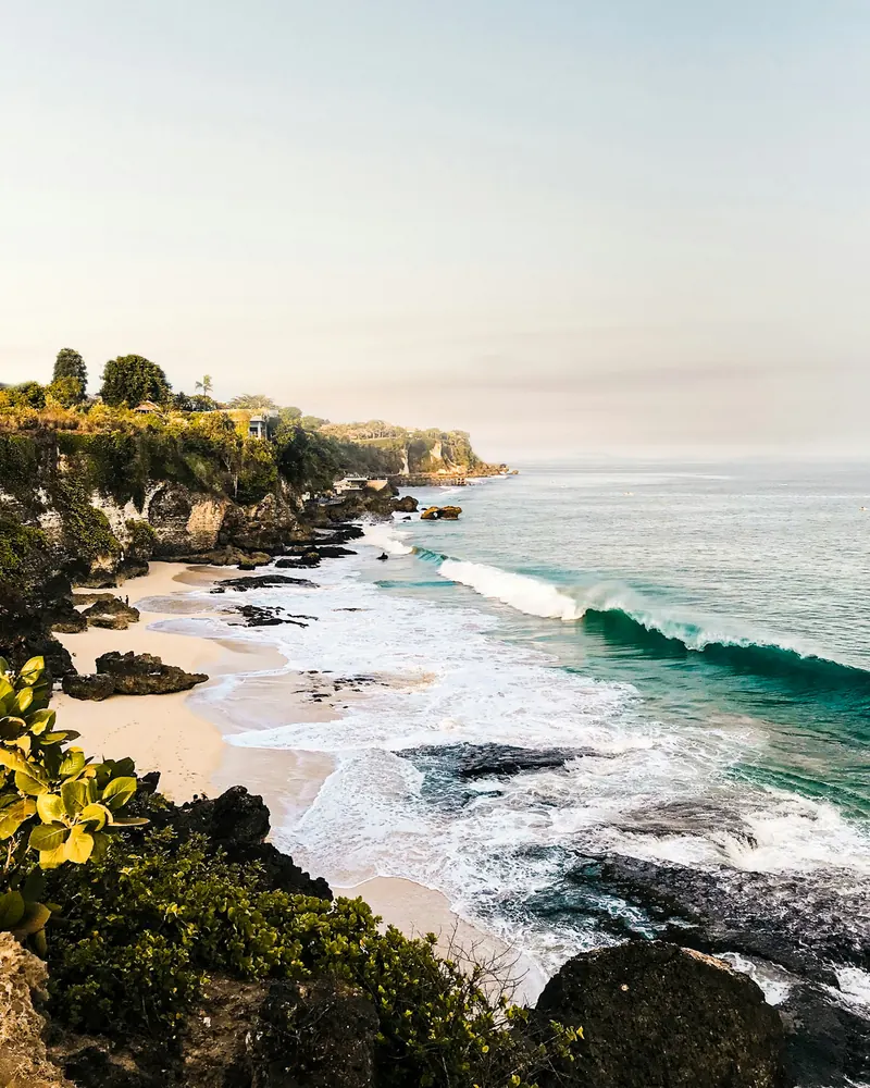 Waves rolling into a cliff-lined beach on Bali's southern coast