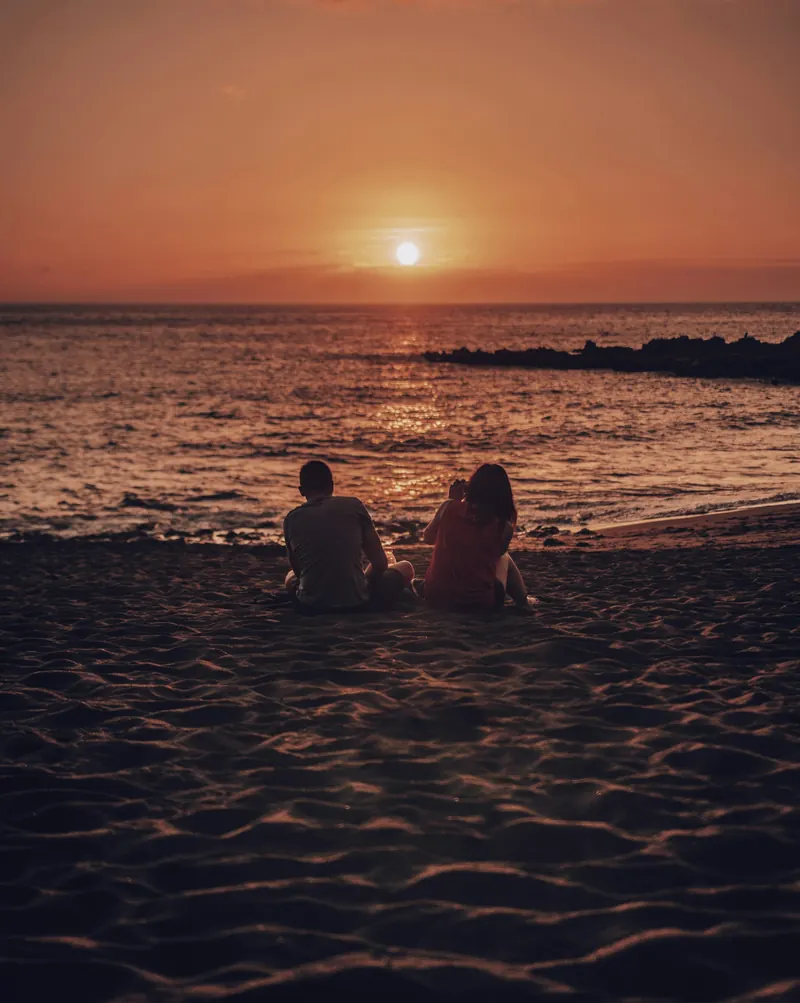 Couple watching a golden sunset on a Bali beach