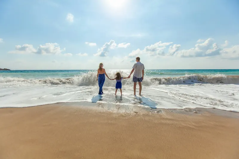 Parents and a child walking hand in hand at the beach