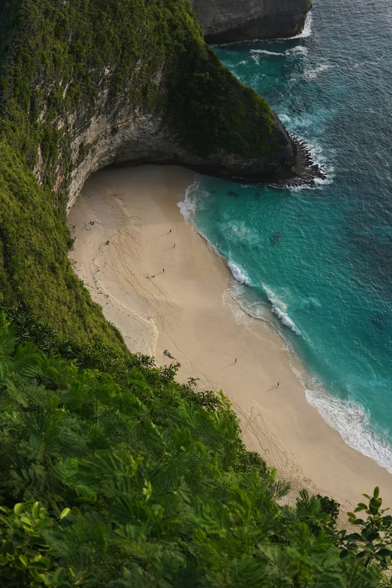 White-sand cove below dramatic cliffs at Kelingking, Nusa Penida