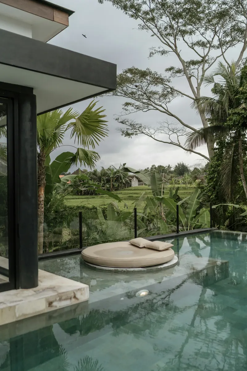 Infinity pool and daybed overlooking green Bali countryside