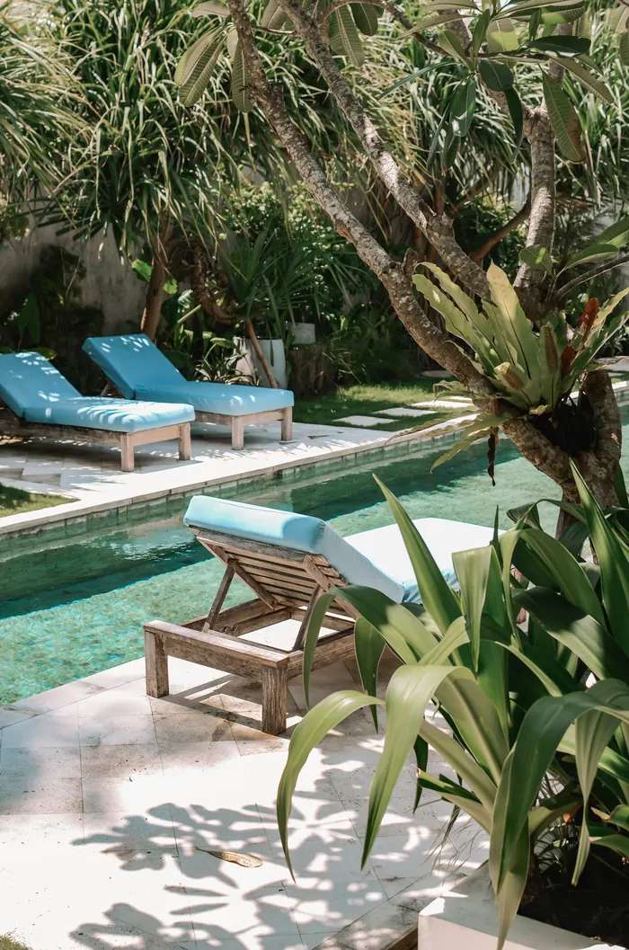 Sun loungers beside a tropical villa pool