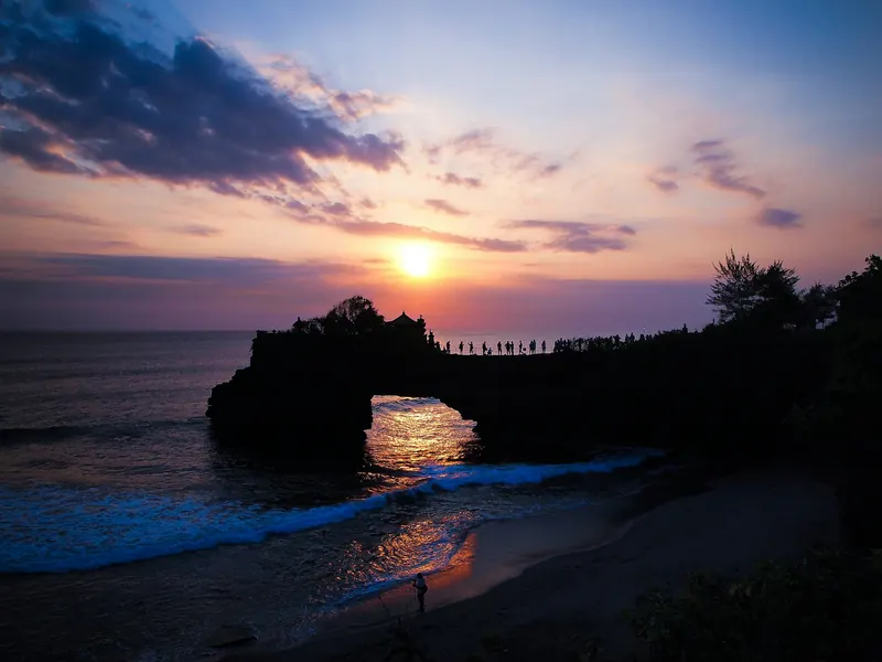 Golden Bali sunset over the ocean through a rock arch
